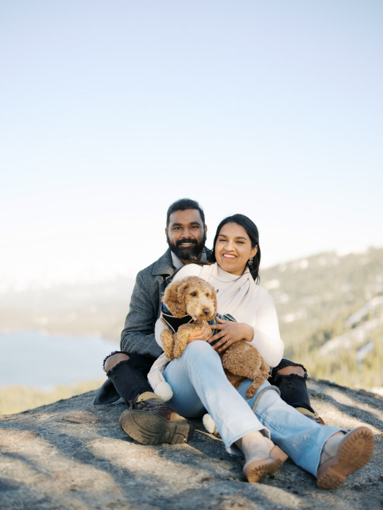 Couple sitting in a rock at donner lake overlook whule holding their dog