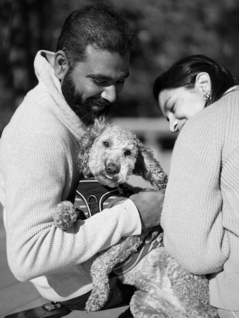 Close up of couple sitting with their dog in a pier at donner lake, the dog is being silly and the couple smiles