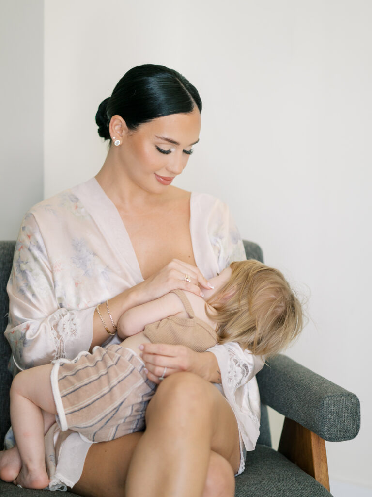 Bride in floral robe nursing baby on wedding morning, Tampa destination wedding