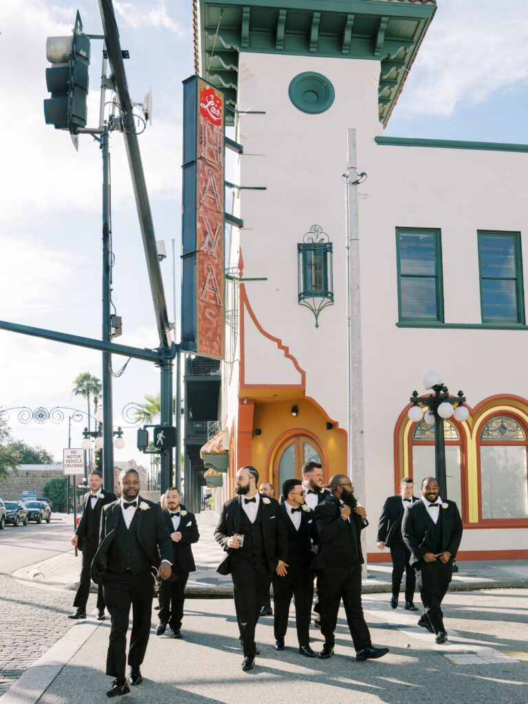 Groom and groomsmen in black tuxedos walking through Ybor City streets, Tampa destination wedding