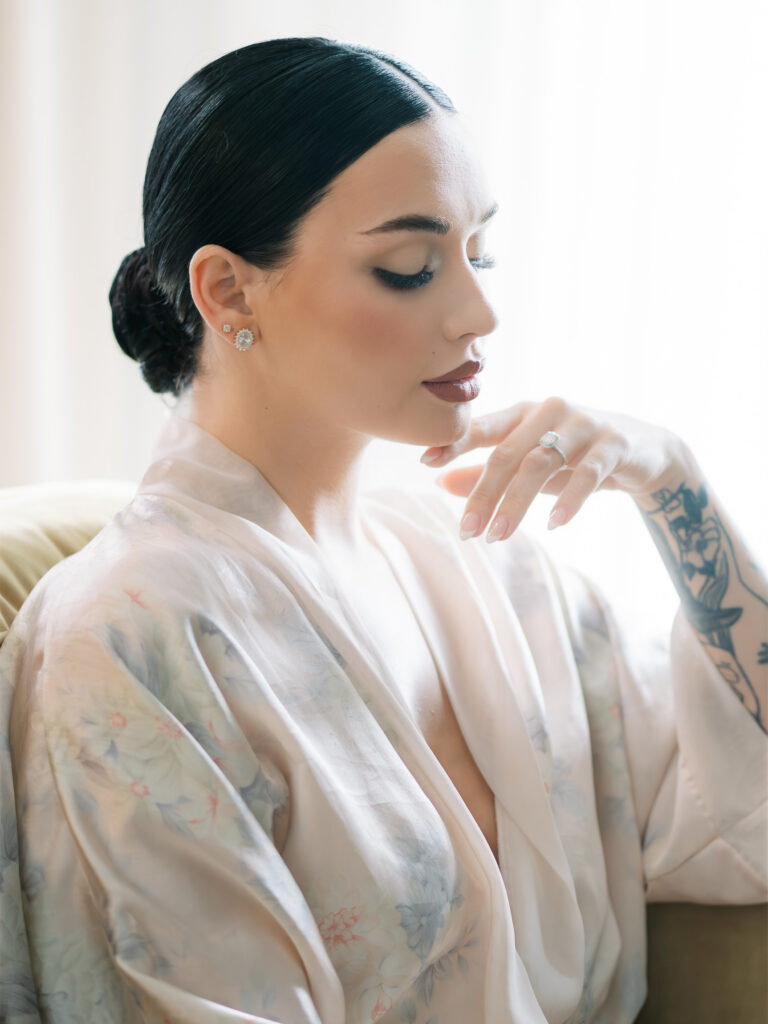Bride in floral robe with sleek updo and diamond earrings, fine art wedding portrait Tampa