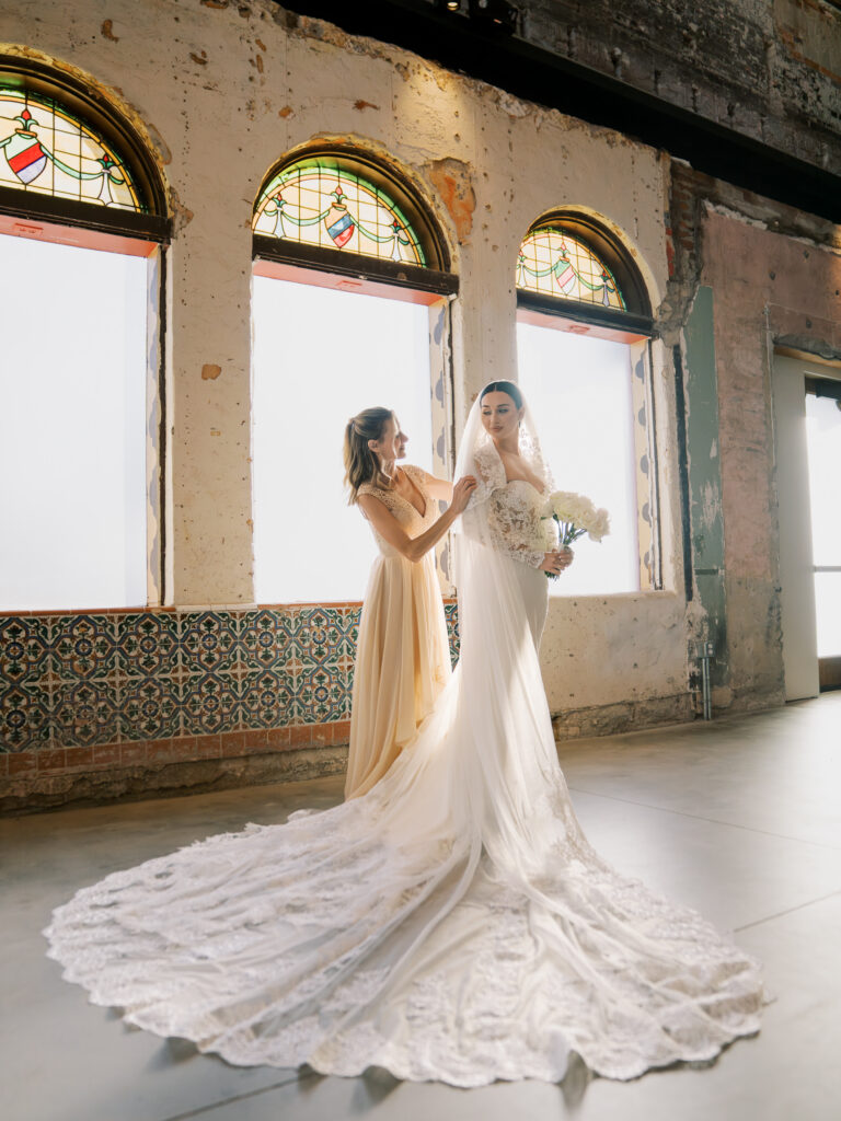 Bride and mother standing near arched stained glass windows, Tampa destination wedding fine art photography