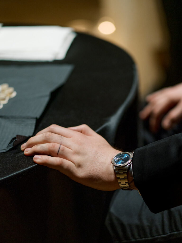 Groom's hand with wedding band tattoo and luxury watch during ceremony, Tampa wedding detail photography