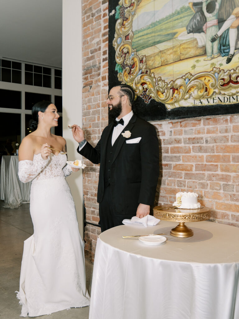 Bride and groom cutting cake in front of hand-painted Italian mural, Ybor City wedding reception