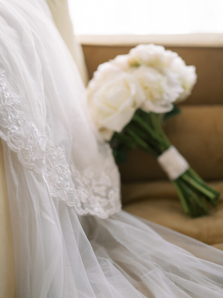 White peony bridal bouquet resting against cathedral lace veil, Ybor City wedding details