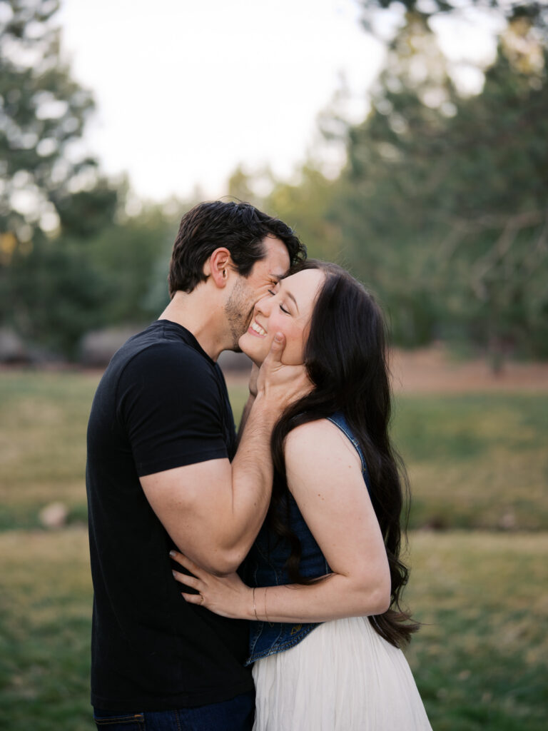 A couple where he kisses his girlfriend captured by a Reno photographer in a couples session