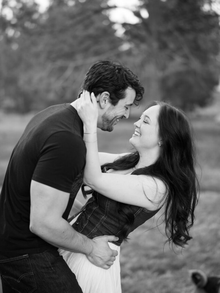 Couple laughing at each other while she holds herself from his neck captured by a Reno photographer in a couples session